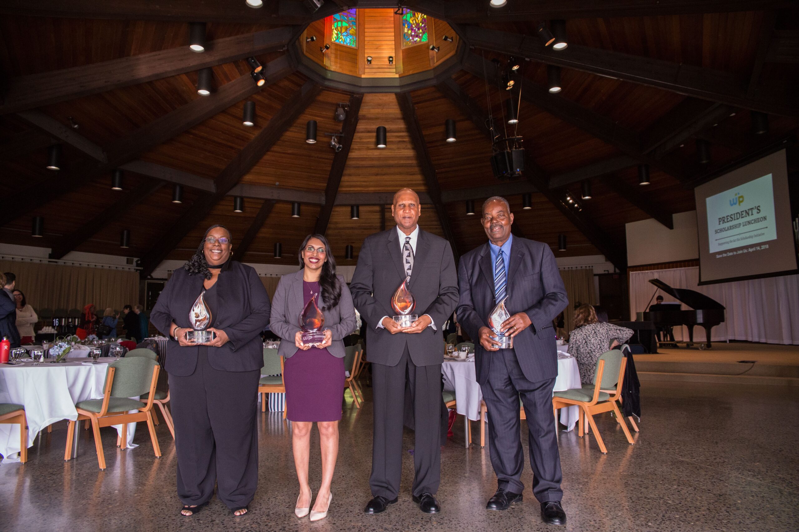 Photo of four alumni with awards