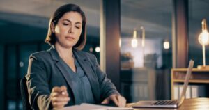 A paralegal reviews documents while seated at a desk with a laptop.