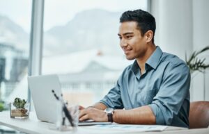 A business administration professional sitting at a desk in front of a laptop.